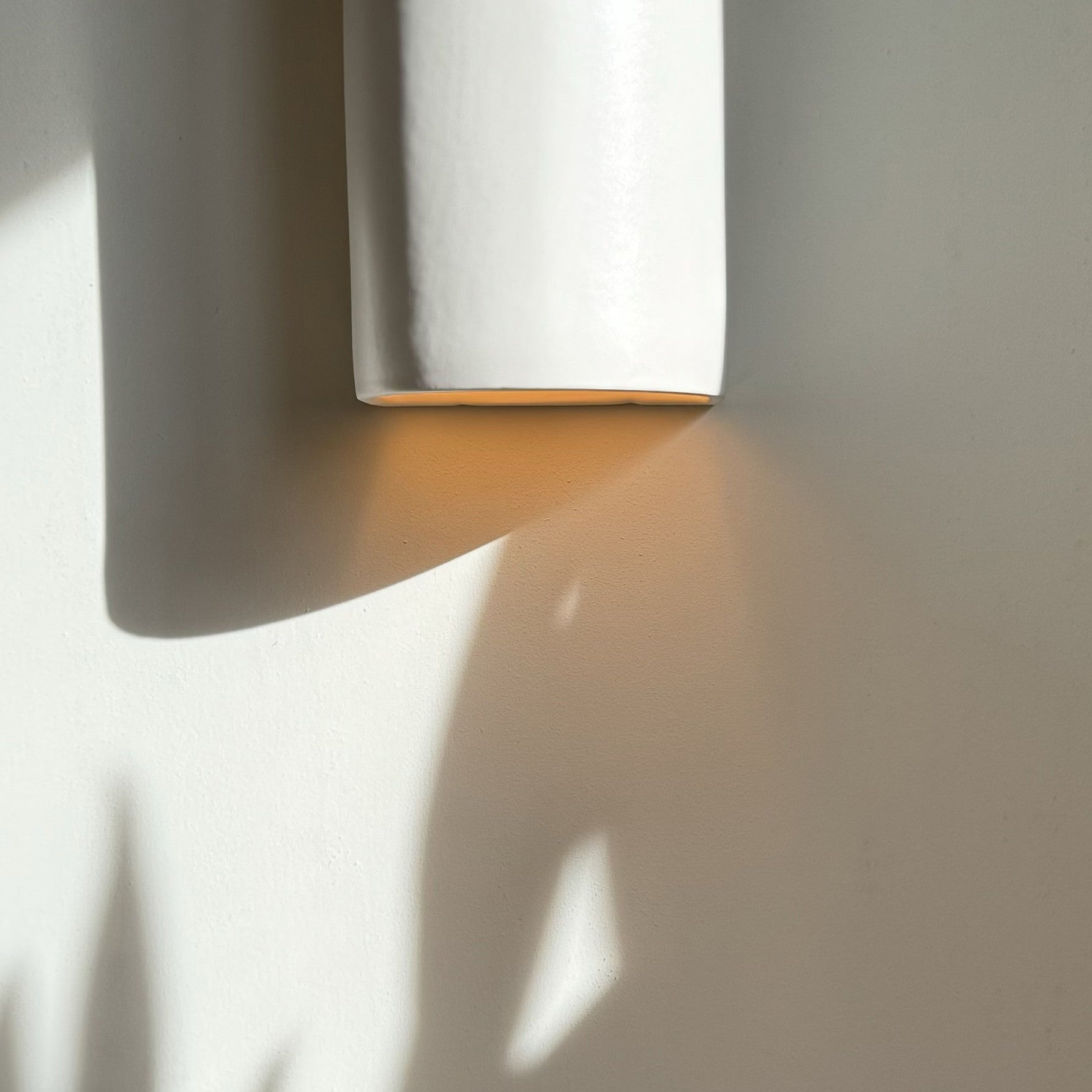 elegant off-white ceramic wall light casting a soft, refined glow in a sophisticated hallway