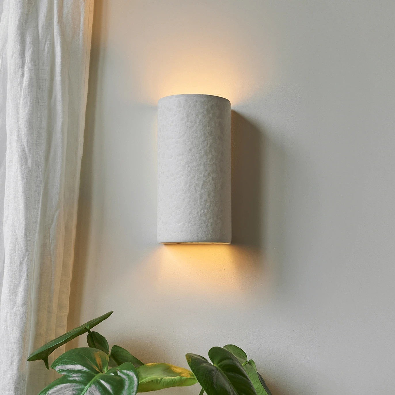 bold raw white ceramic wall light casting a dramatic sculptural shadow