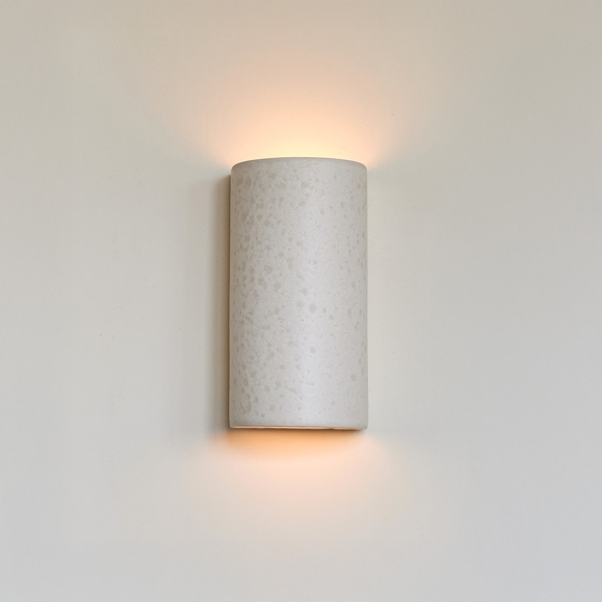 a softly glowing raw white ceramic wall light casting a gentle, comforting glow in a nursery