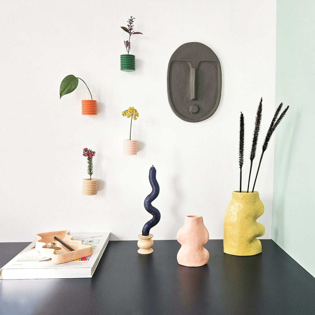 playful abstract ceramic wall mask with a quirky tilt and warm terracotta glow