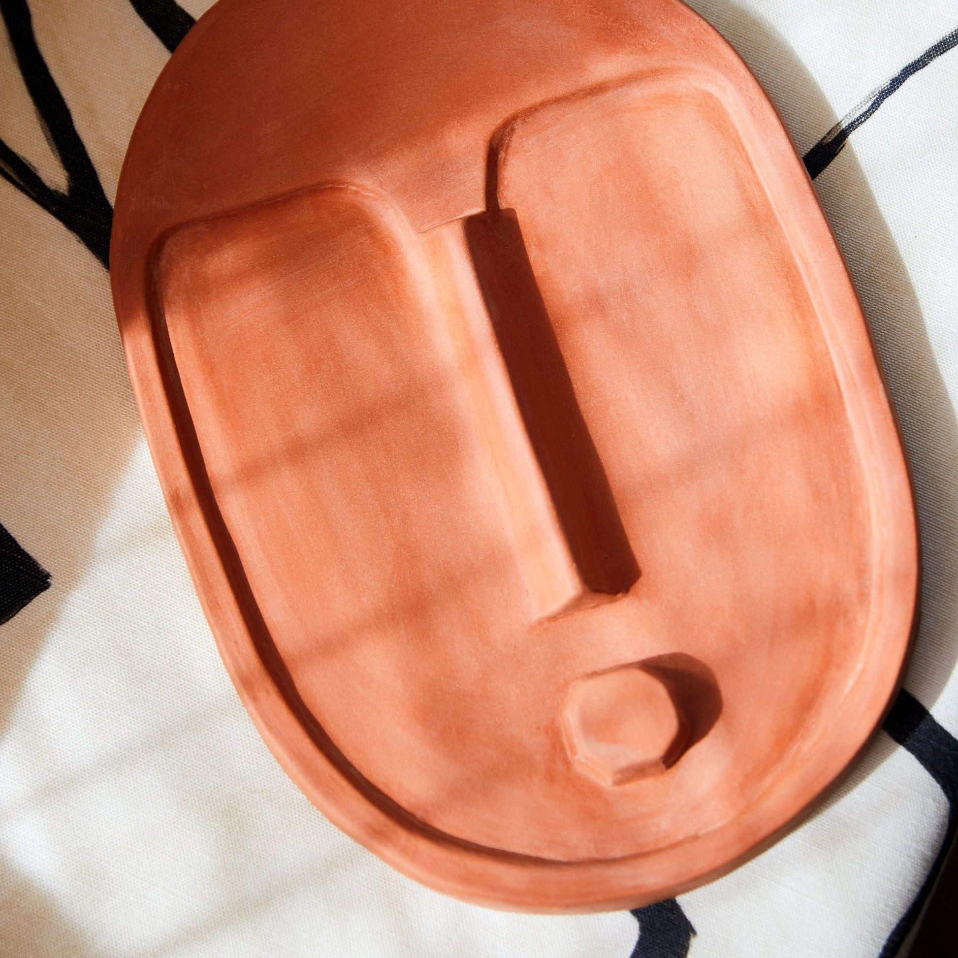 bold handcrafted terracotta wall mask with a striking matte orange glaze