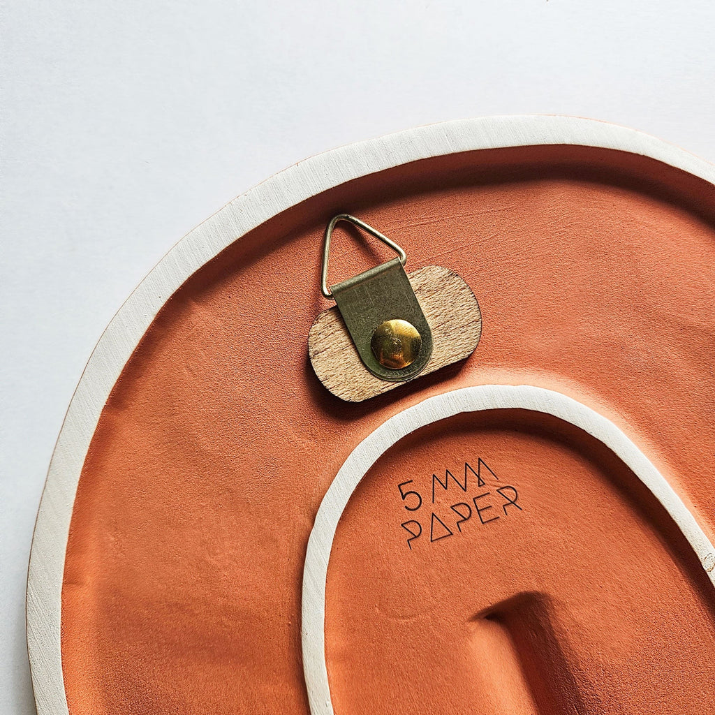 handcrafted portuguese ceramic wall mask with a textured matte terracotta finish in a modern home setting