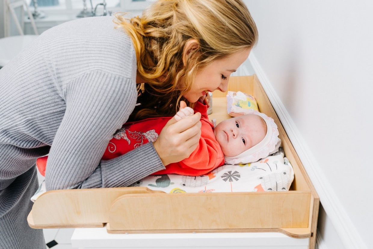 birch changing table top on a chest of drawers in a warm nursery