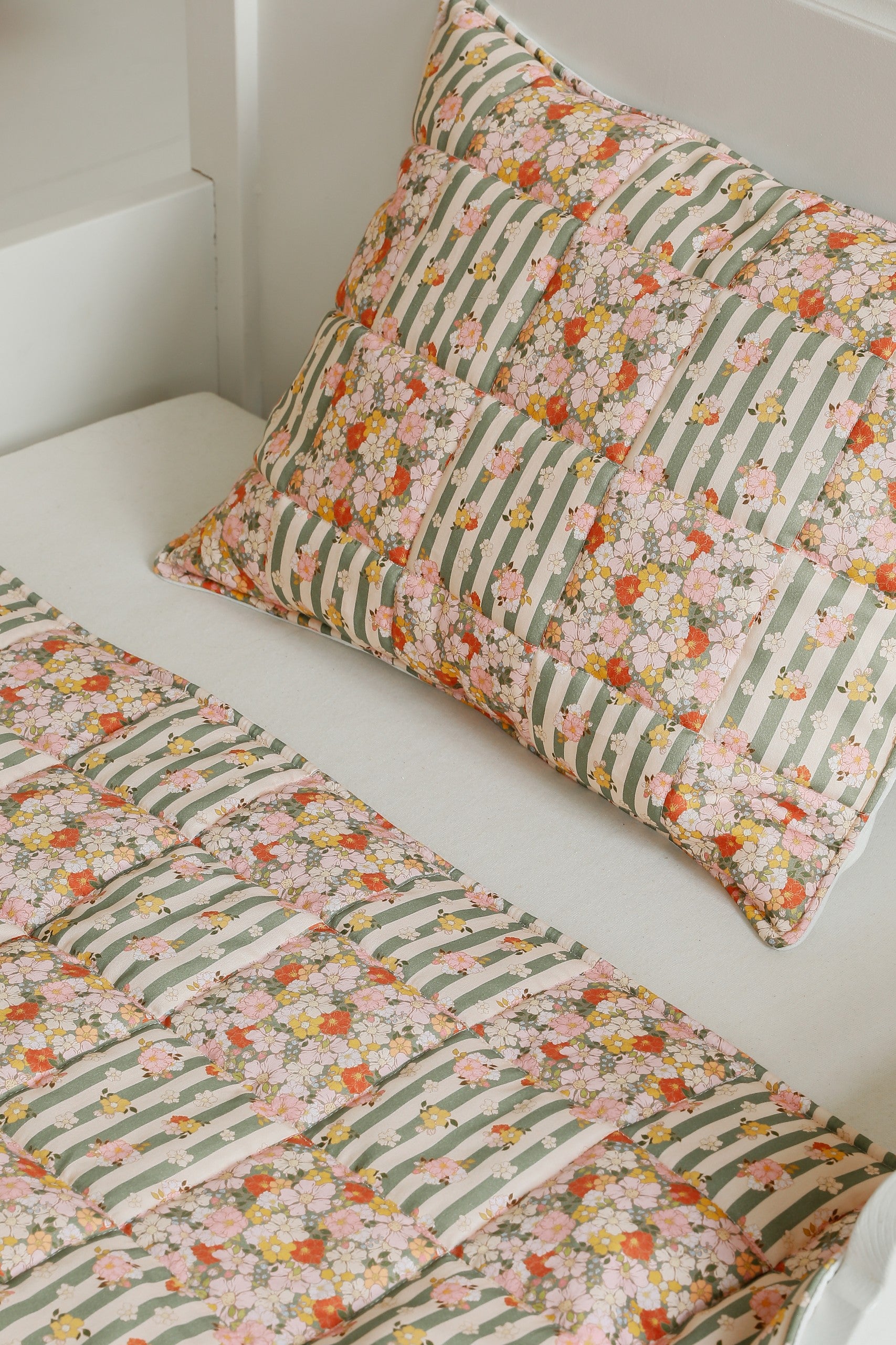 soft green garden cotton quilted blanket and pillow set laid on a cozy bed, gentle patchwork patterns in natural light