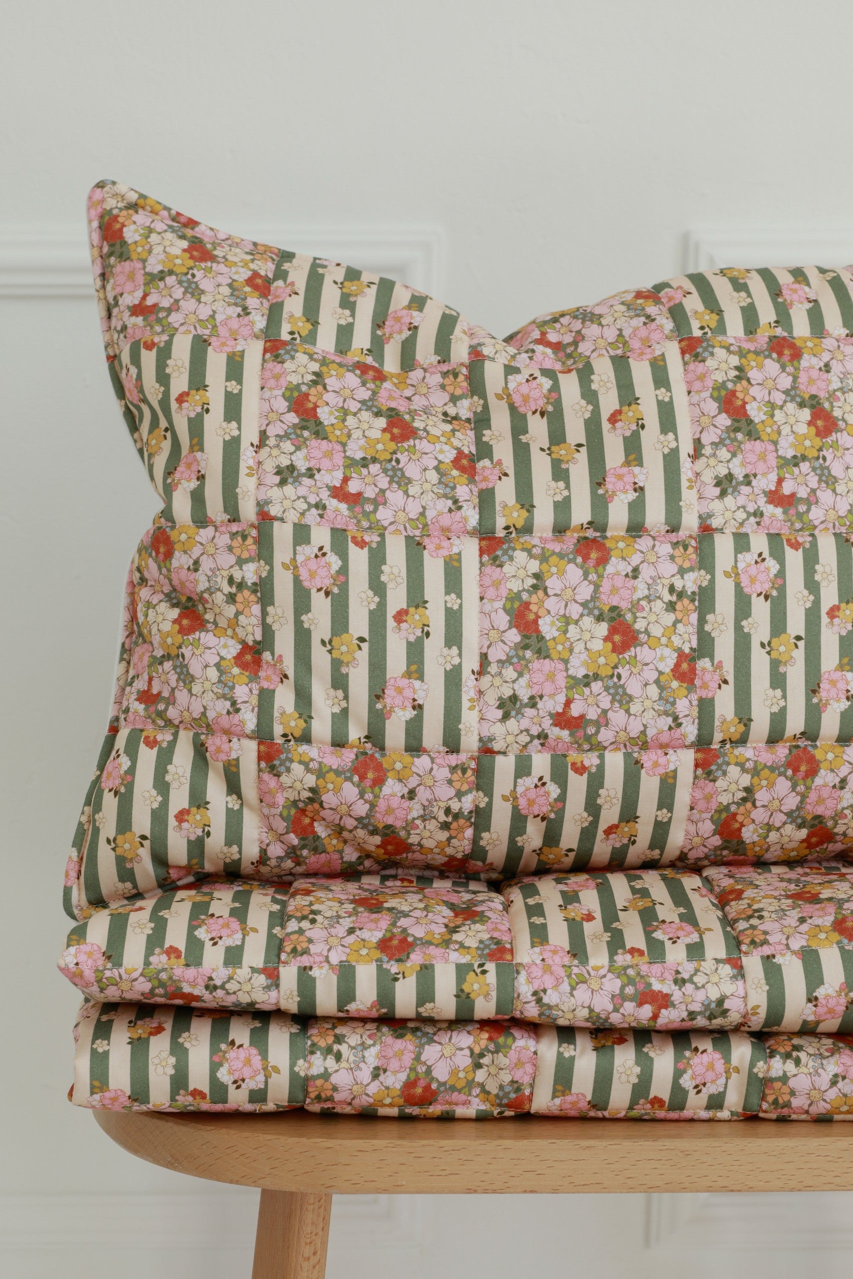 bold green garden quilted blanket and pillow set laid flat on a wooden floor, showcasing patchwork details