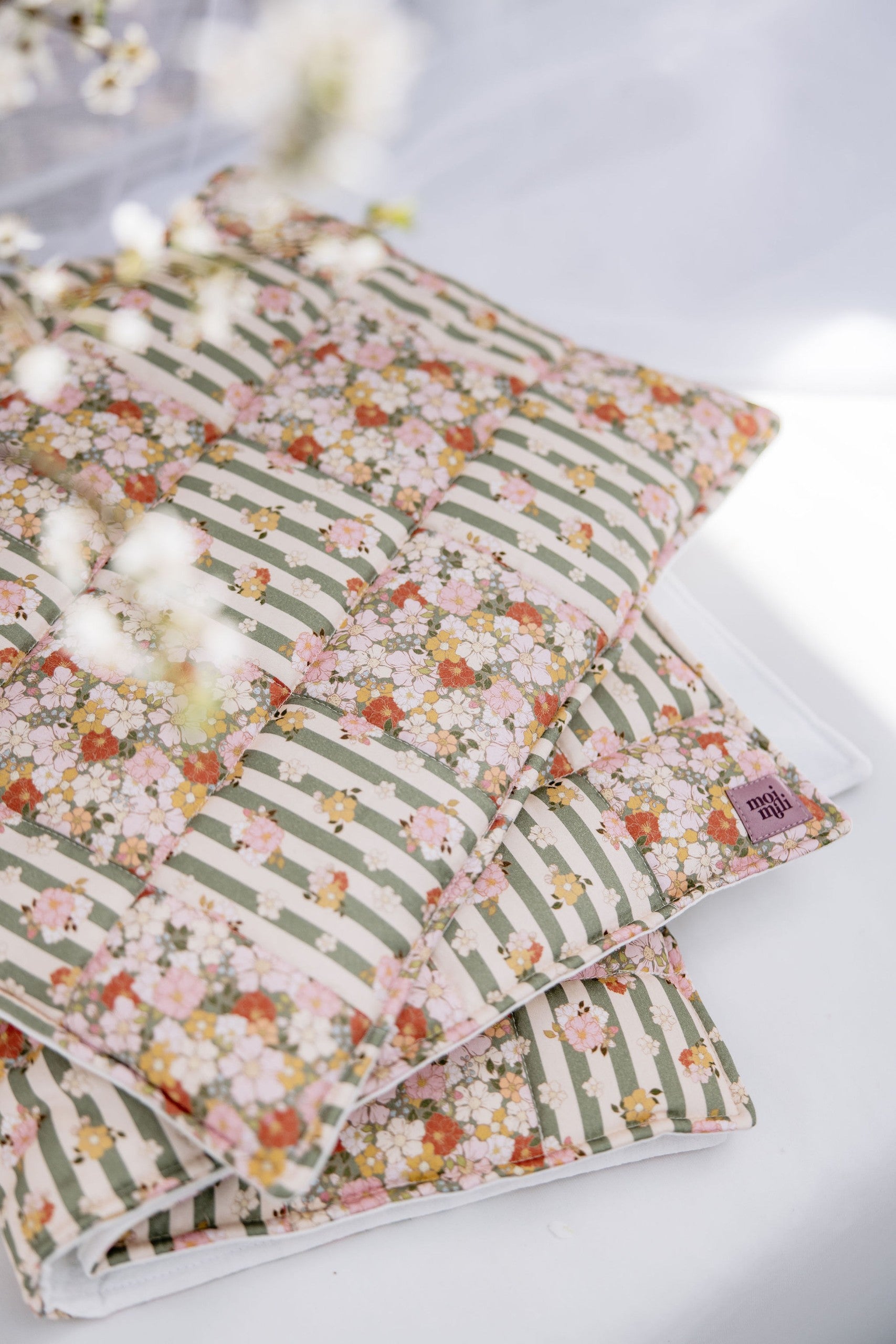 elegant green garden quilted blanket and pillow set laid on a rustic wooden bench, showcasing intricate patchwork details