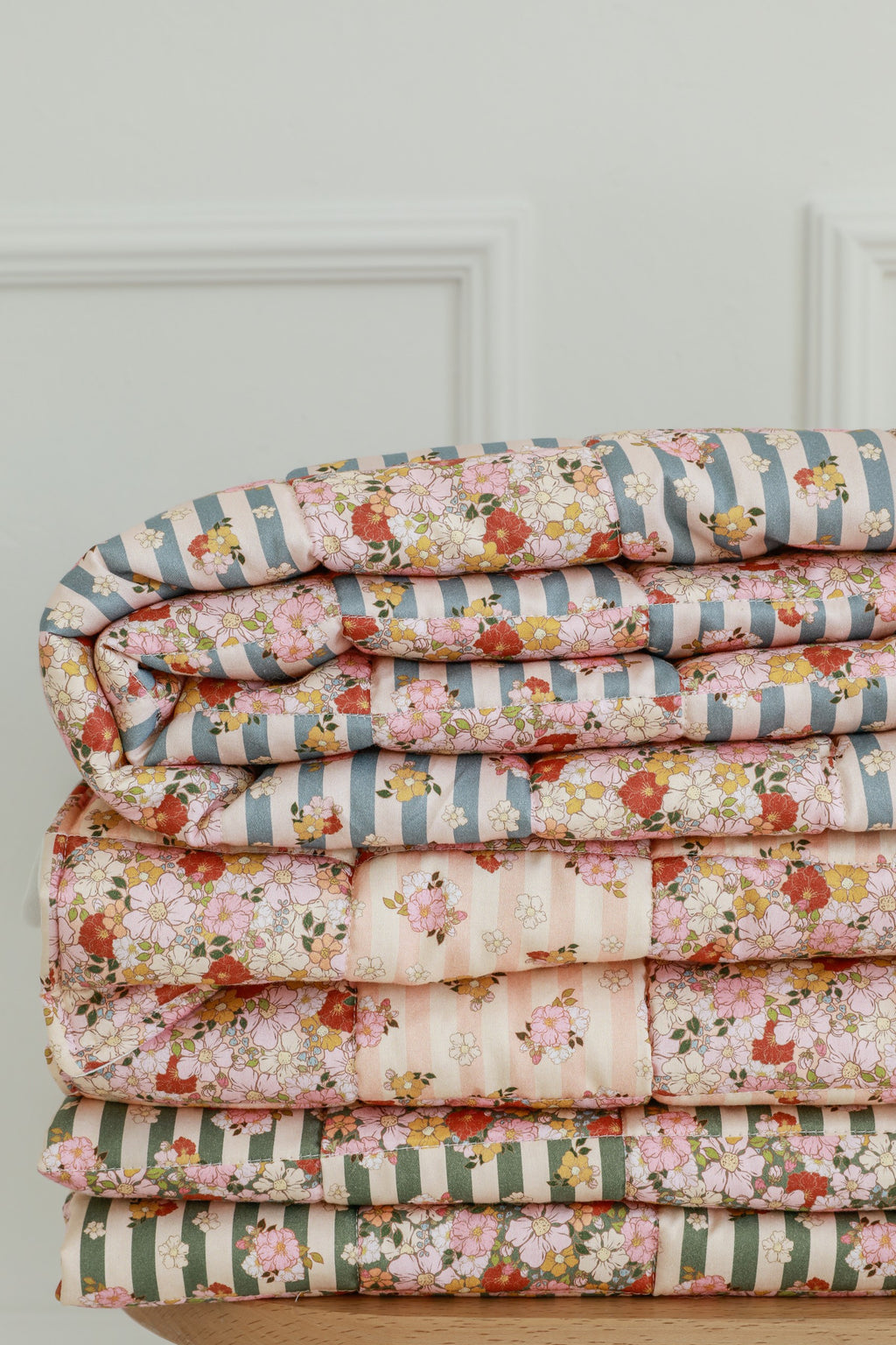 soft cotton quilted patchwork blanket and pillow set in summer garden colors, draped gently over a cozy nursery chair