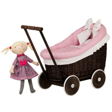 a playful toddler pushing a dark wicker doll pram with cozy pink bedding inside