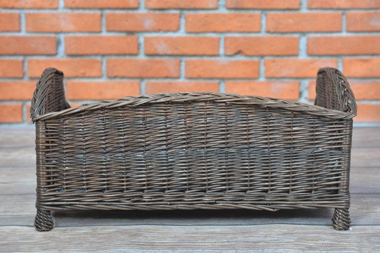 a playful puppy peeking out from the cozy dark wicker pet bed with its soft cushion