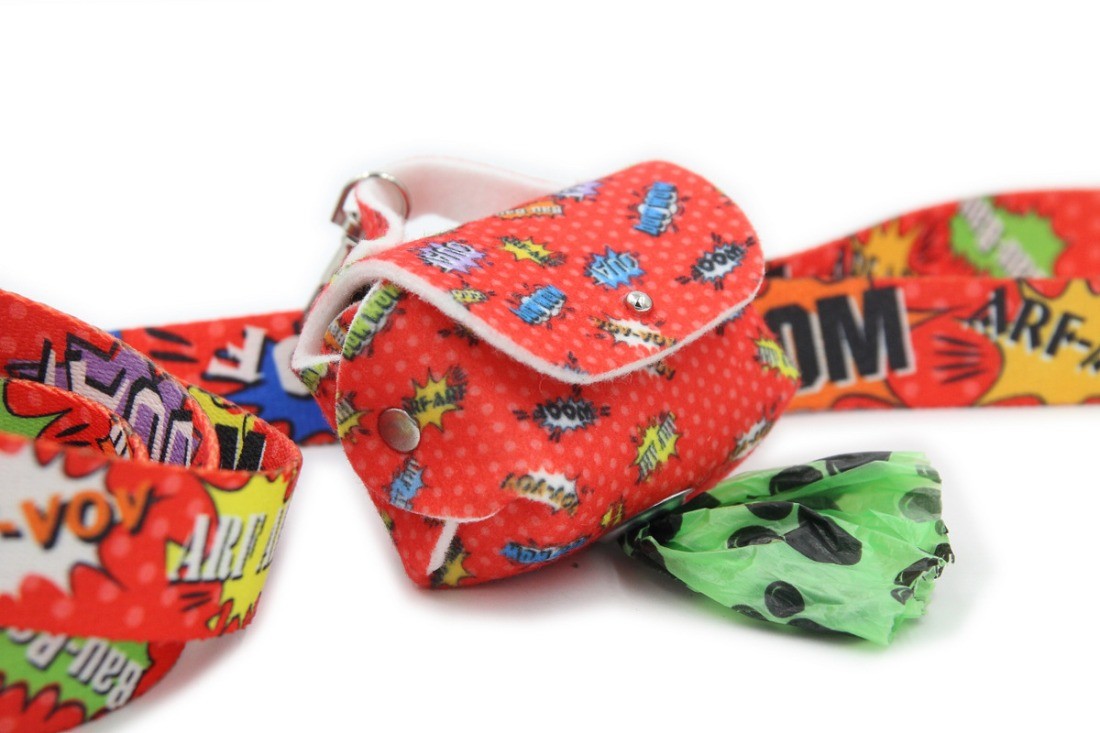 playful red graffiti dog bag dispenser on a leash in the park