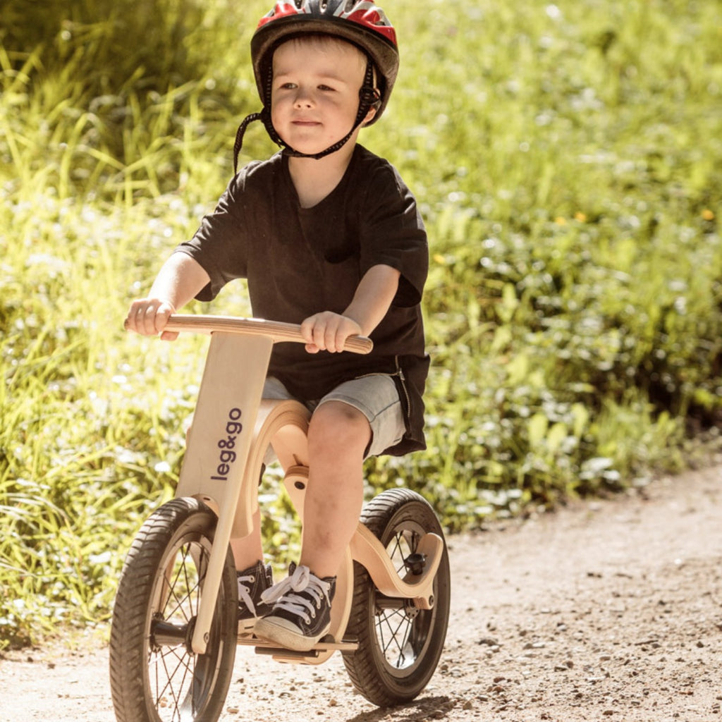 a child's hand pressing the red downhill brake on a balance bike, ready for fun