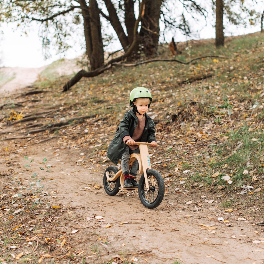 a child's foot pressing the downhill brake on a balance bike in soft morning light