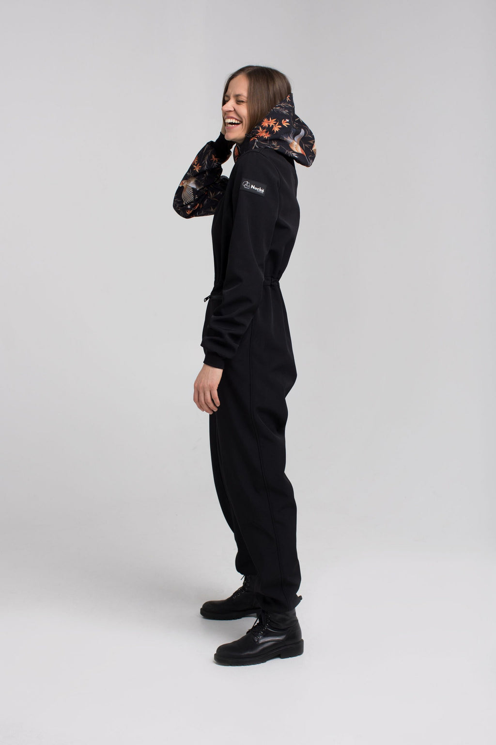 a toddler in a playful waterproof onesie jumping joyfully in a puddle on a rainy day