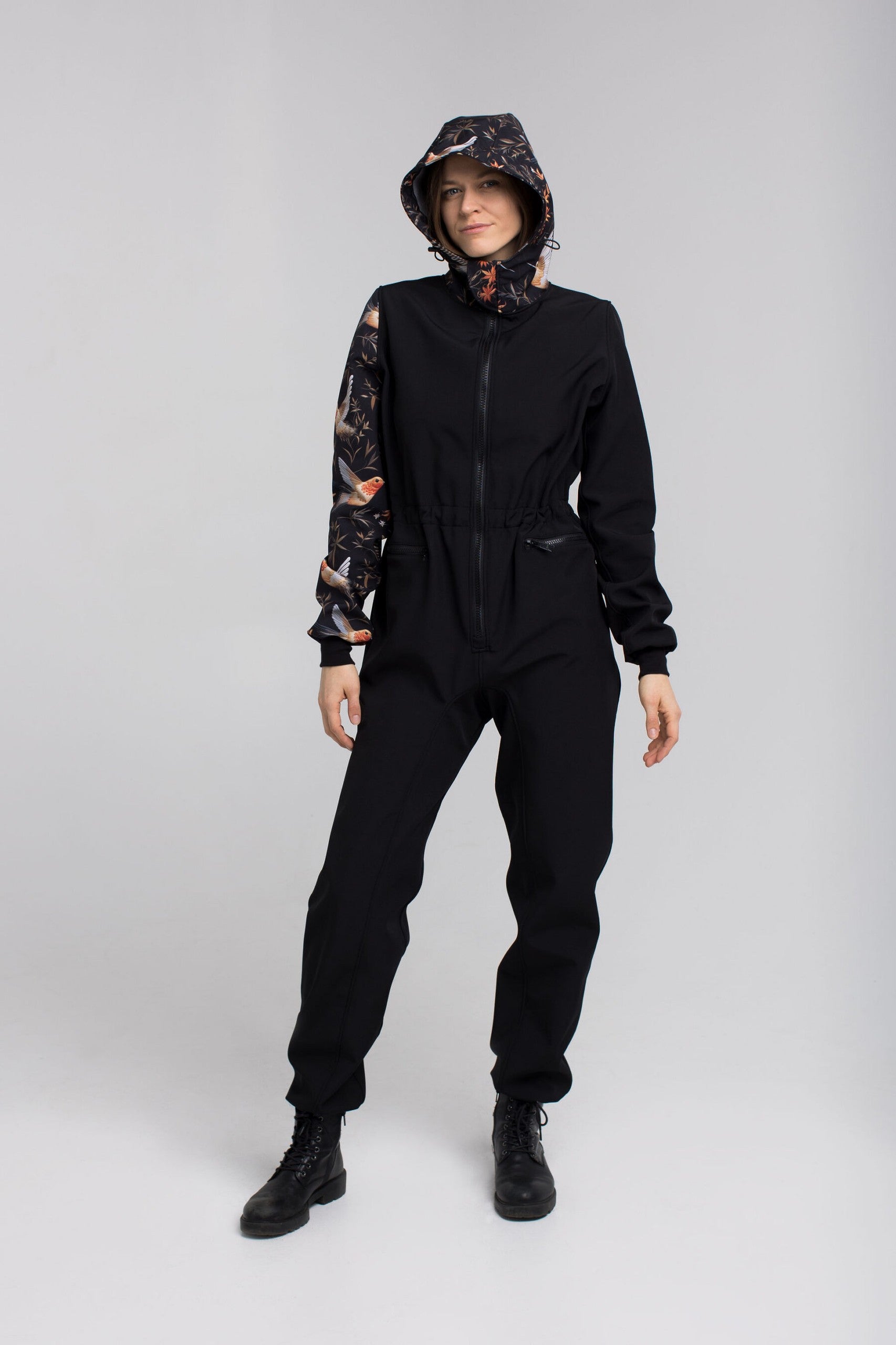 a child in a softshell waterproof onesie standing on a forest path, ready for rain