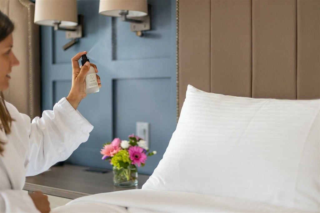 practical shot of eucalyptus room spray bottle on a bathroom countertop next to towels