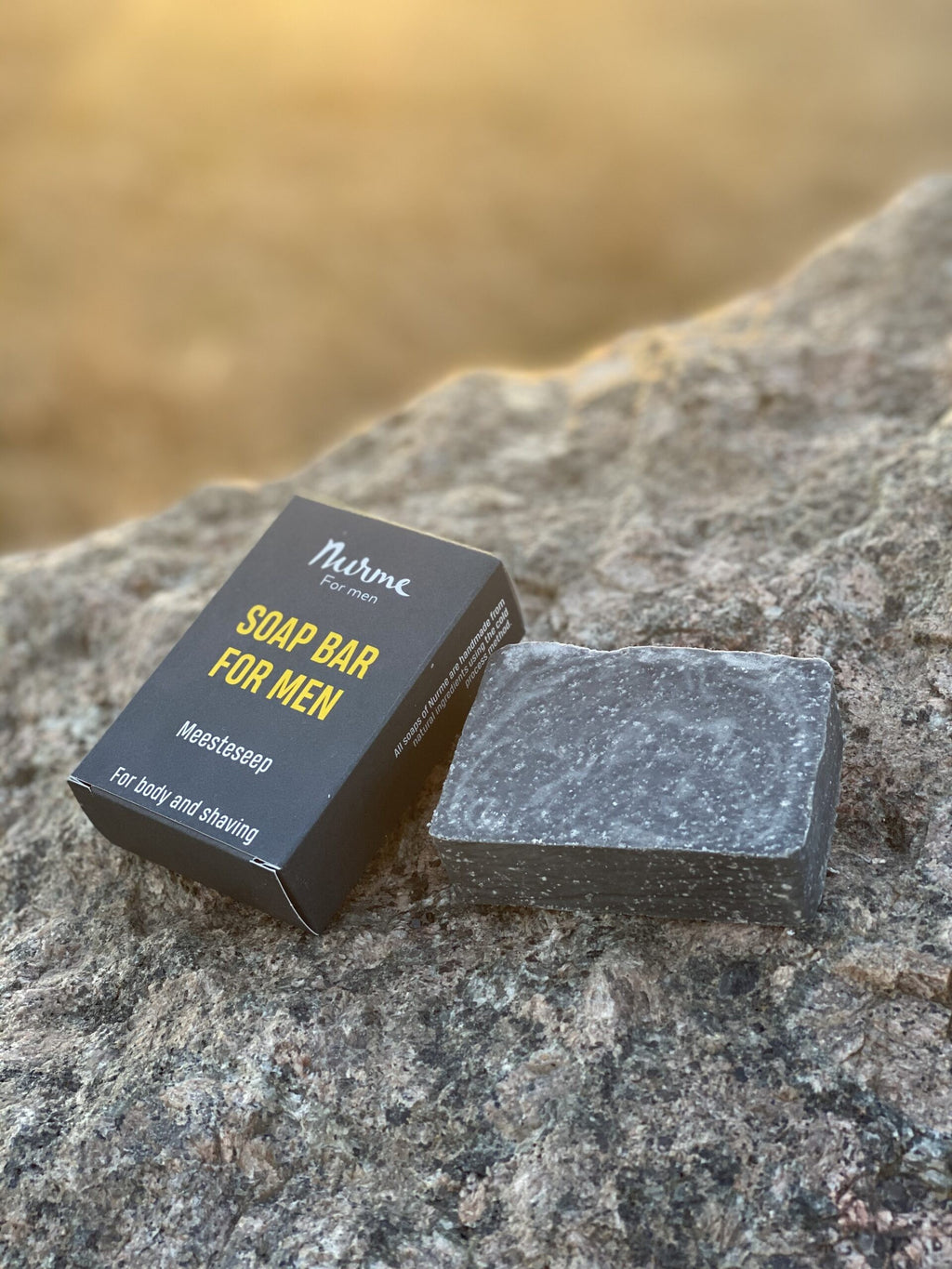 a bold close-up of a men's charcoal and sage soap bar on dark slate