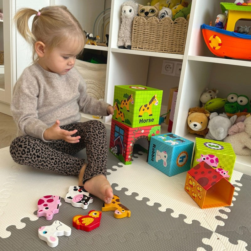a child's hand stacking the smallest farm cube with a chick peeking out