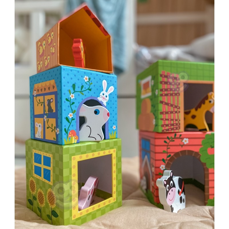 child's hand stacking a vibrant farm cube puzzle with a wooden cow