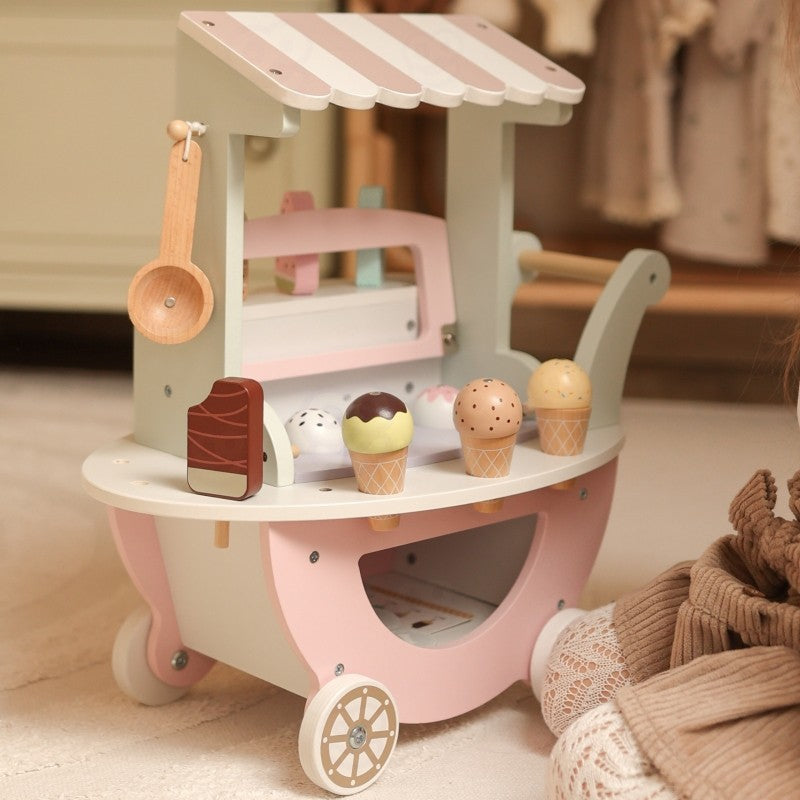child's hand holding a magnetic pastel ice cream scoop from the woopie green wooden cart