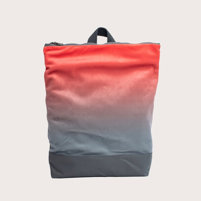 stylish salmon faux leather backpack on a park bench in soft morning light