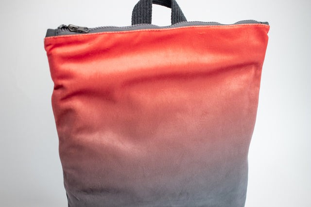 functional salmon faux leather backpack with multiple pockets and laptop compartment, shown in warm morning light