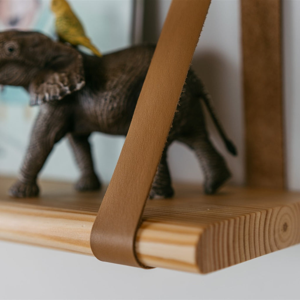 a playful floating wooden shelf with leather straps holding colorful kids toys and books