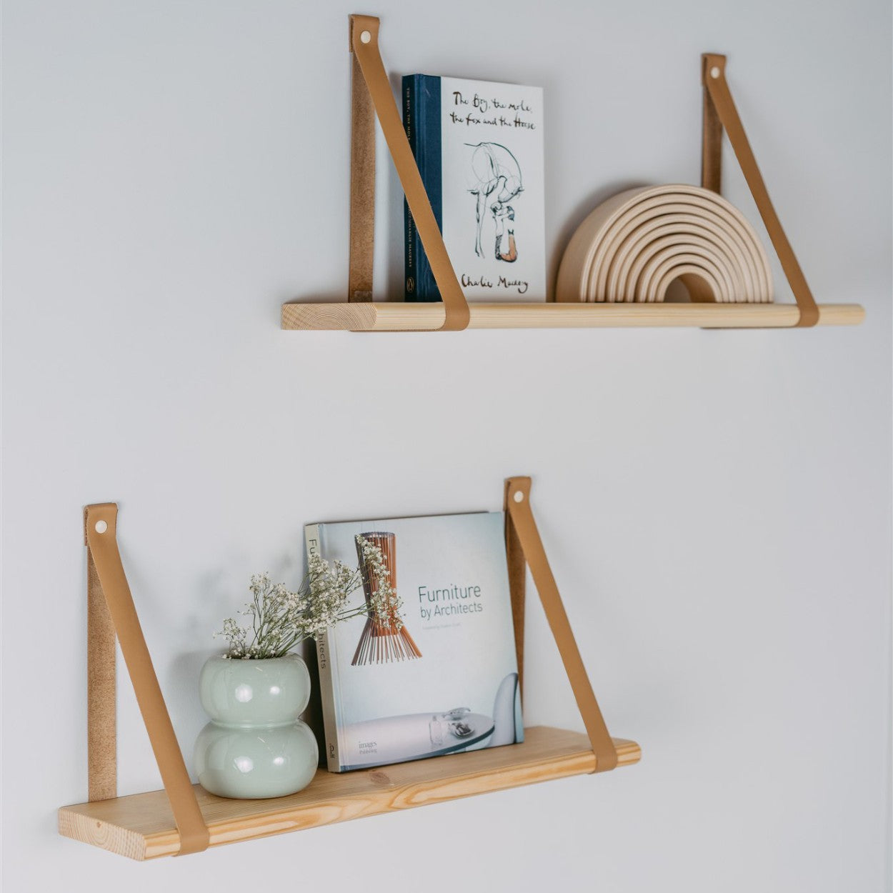 a playful 60 cm pine shelf with camel leather straps in a bright kids room setting