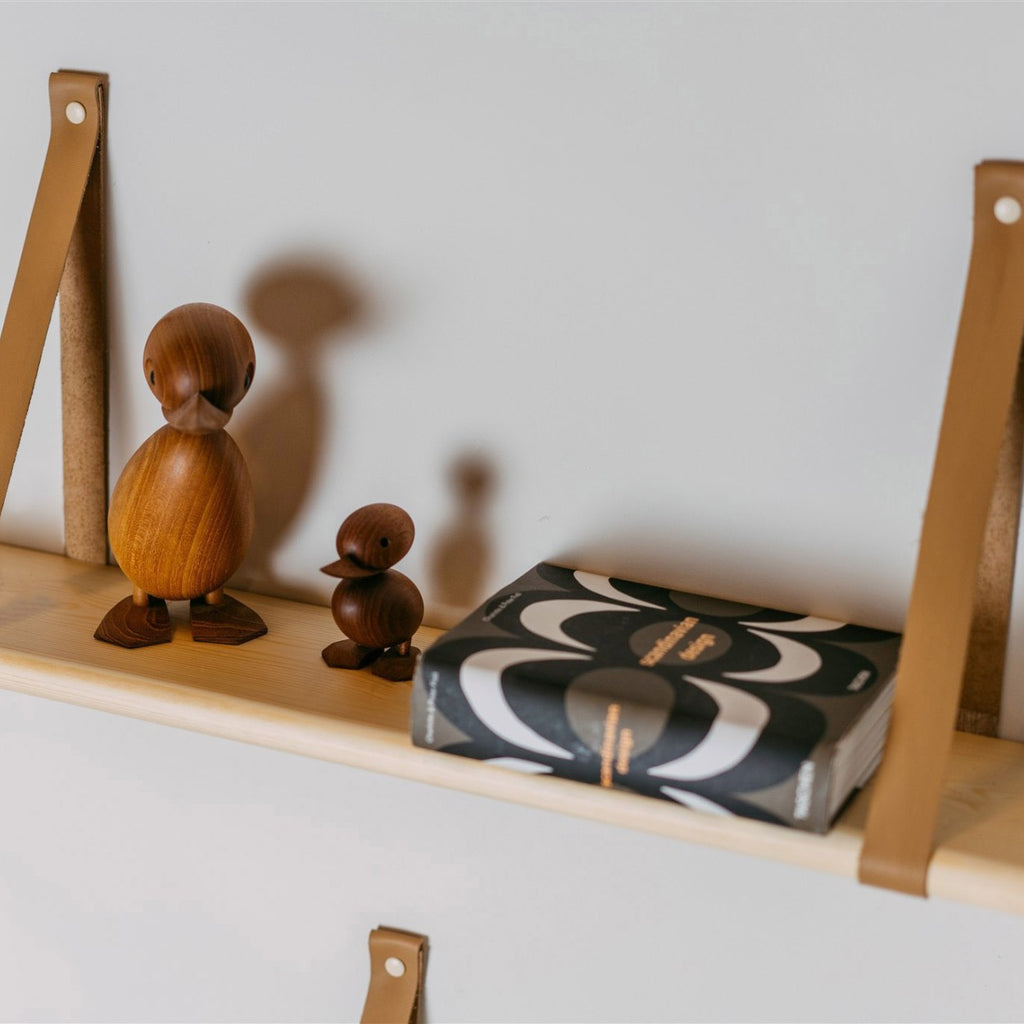 a practical 70 cm floating pine shelf with leather straps holding a stack of baby clothing