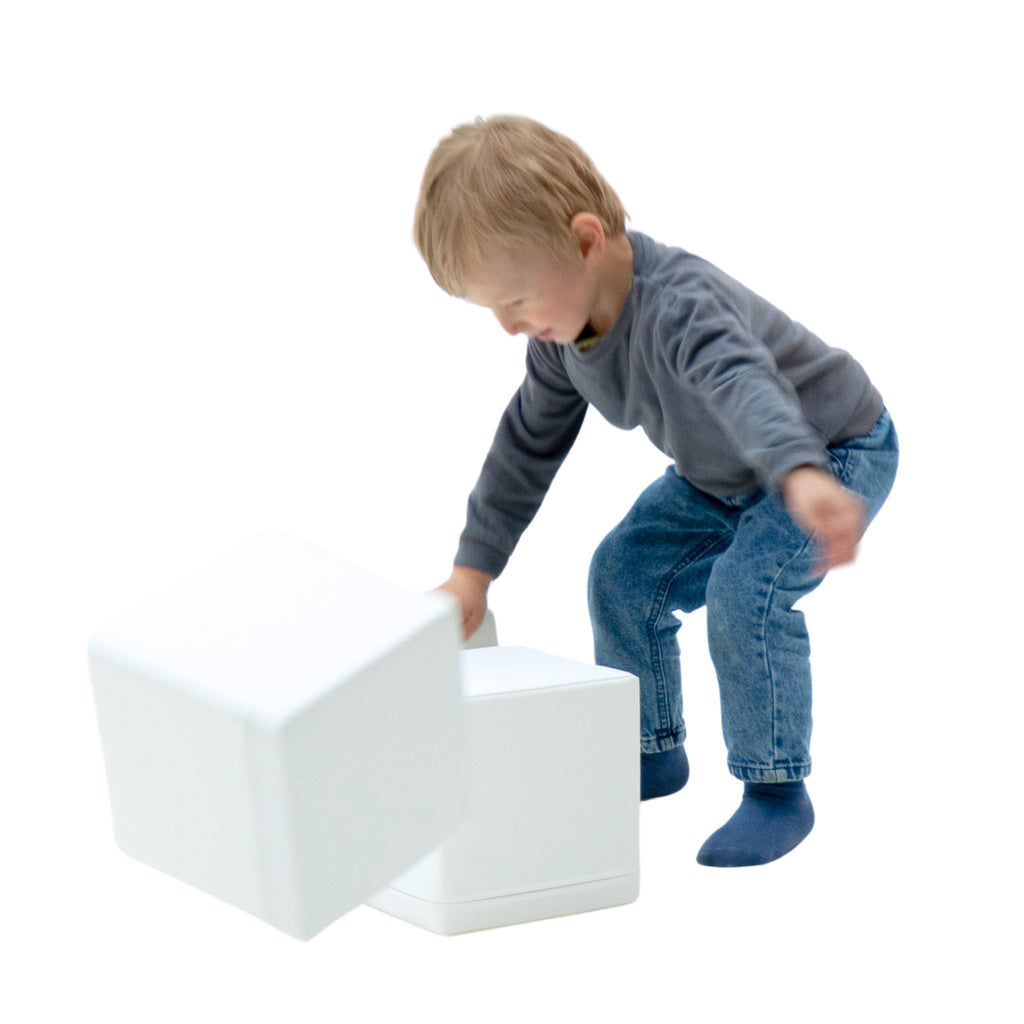 child's hand placing a soft foam block on a colorful igloo structure