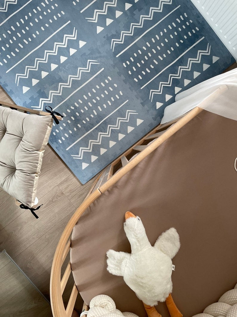 a baby's hand reaching for a soft azure boho puzzle mat during playful tummy time