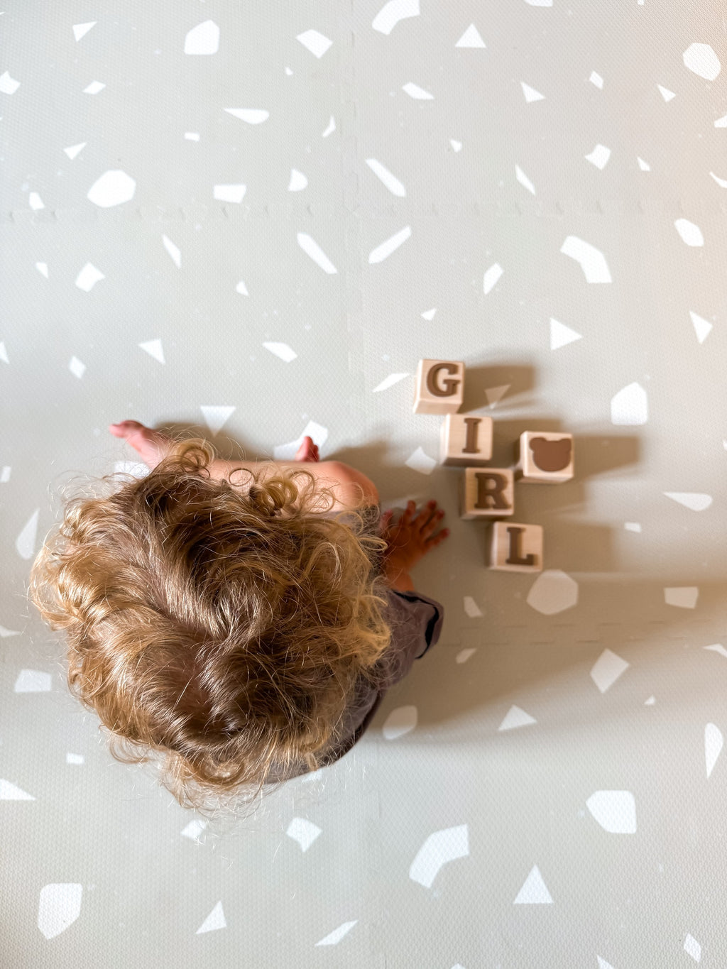 a close-up of a baby playing on a dove terrazzo foam mat, showing off its playful pattern and soft texture
