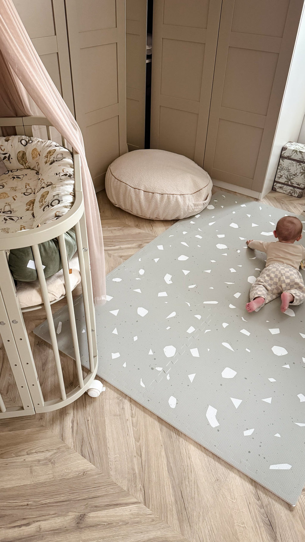 a close-up of the sage terrazzo foam mat with a baby's hand playfully patting the textured surface