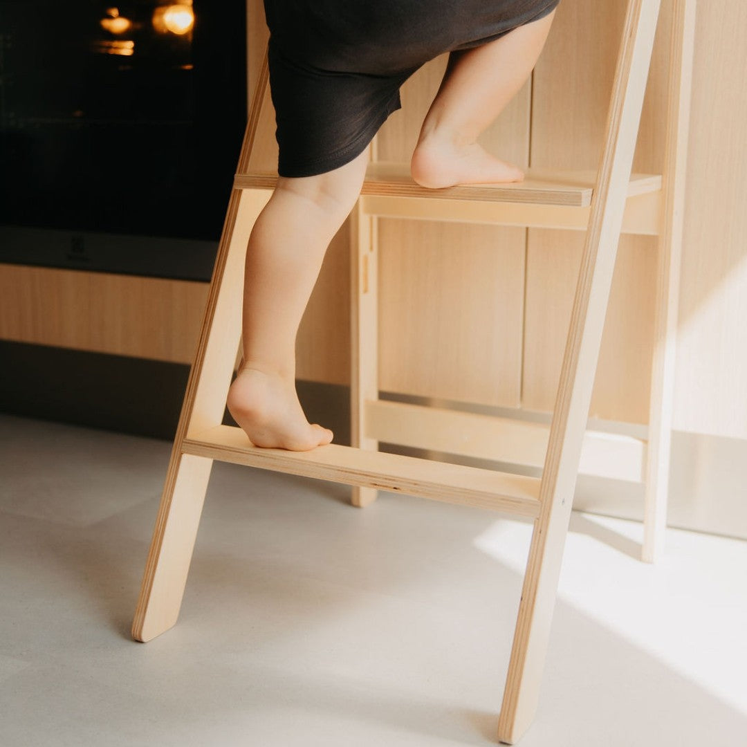 a child safely baking cookies at the counter with a foldable birchwood helper tower