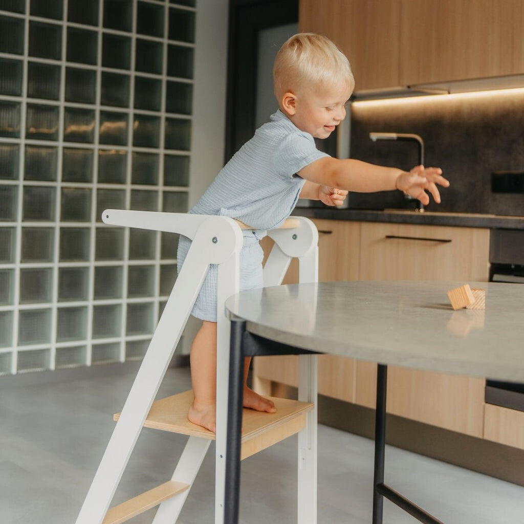 a foldable kitchen helper tower with safety rail in soft morning light, a perfect baby shower gift