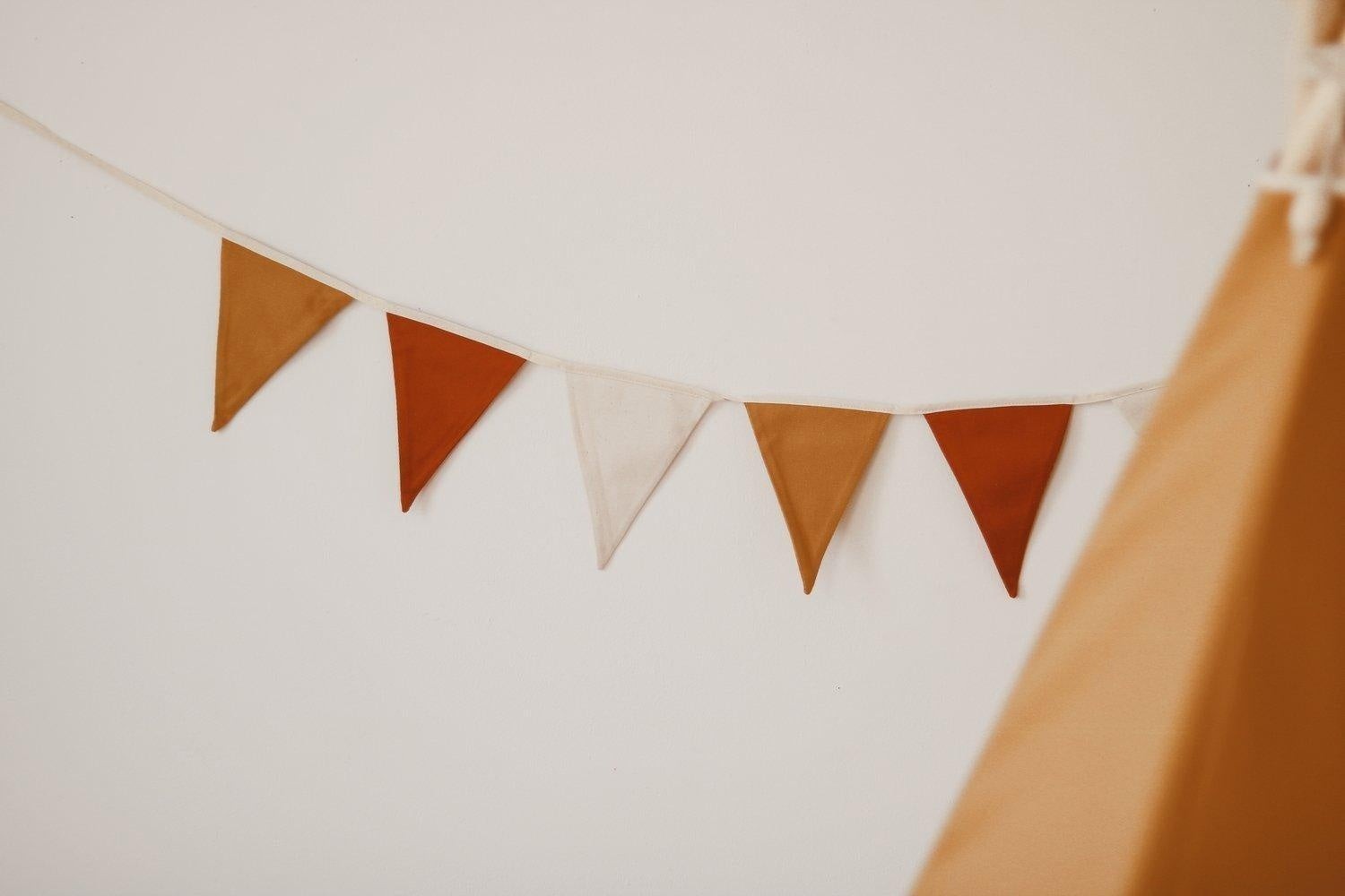 close-up of ochre floral garland showing durable cotton pennants and secure hanging loop