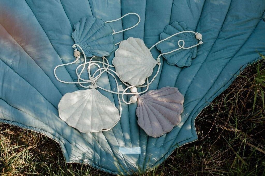 elegant dusty blue shell garland with linen pendants and wooden beads, displayed against a refined neutral background
