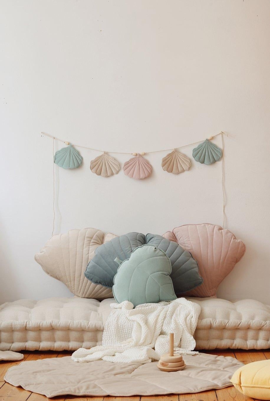 soft pastel shell garland draped over a wooden crib, glowing in warm sunlight, creating a dreamy nursery decor