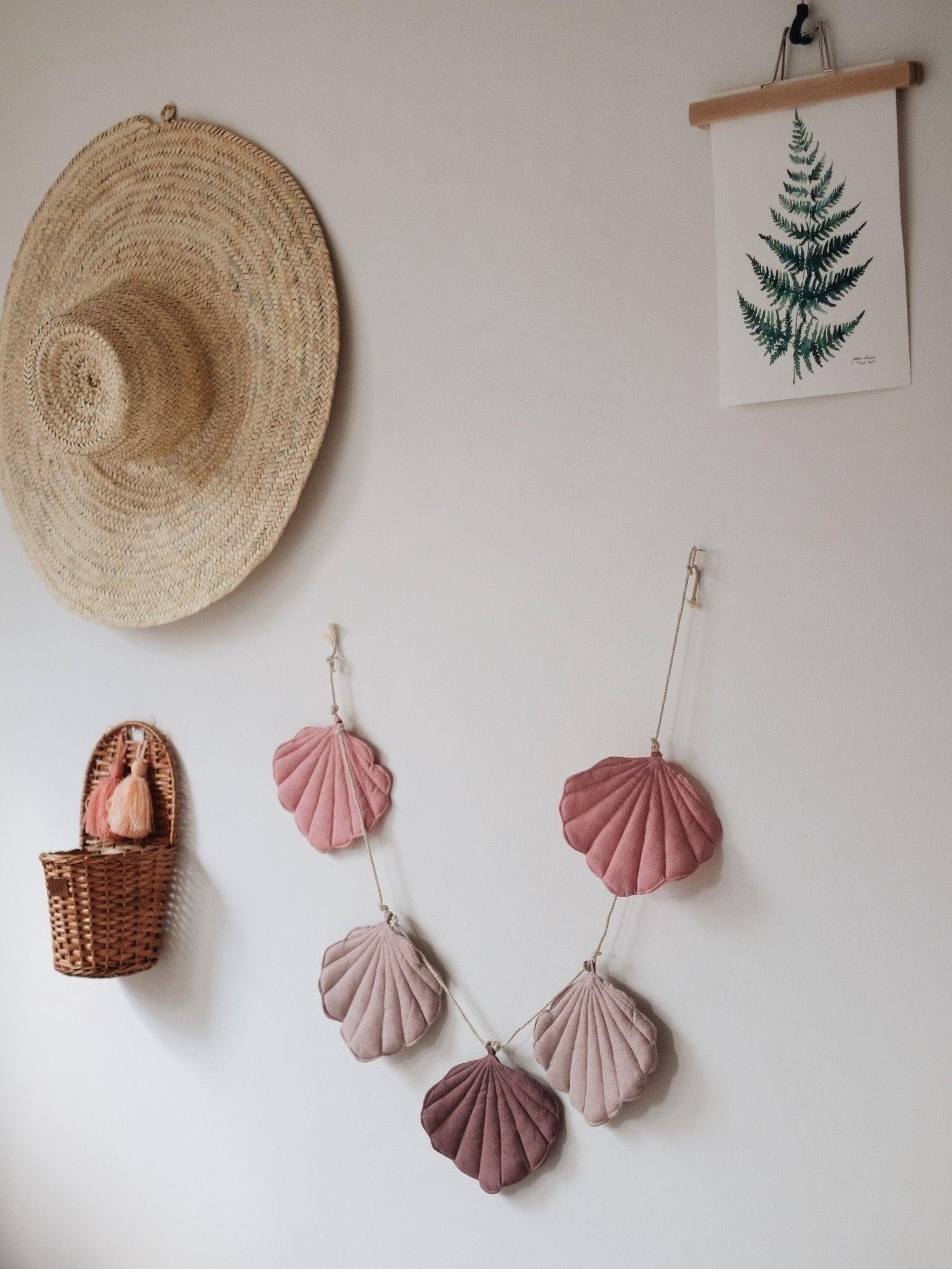 bold powder pink shell garland draped dramatically across a dark wall