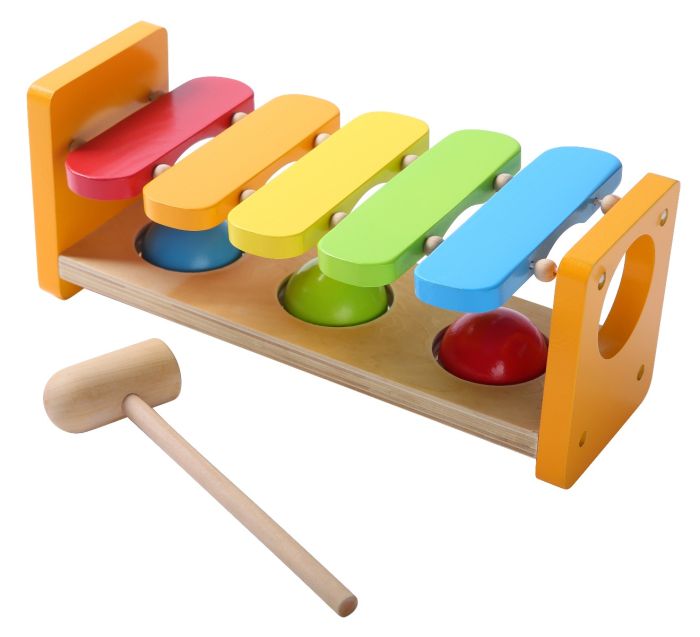 soft-lit close-up of a child gently tapping the wooden xylophone hammer bench