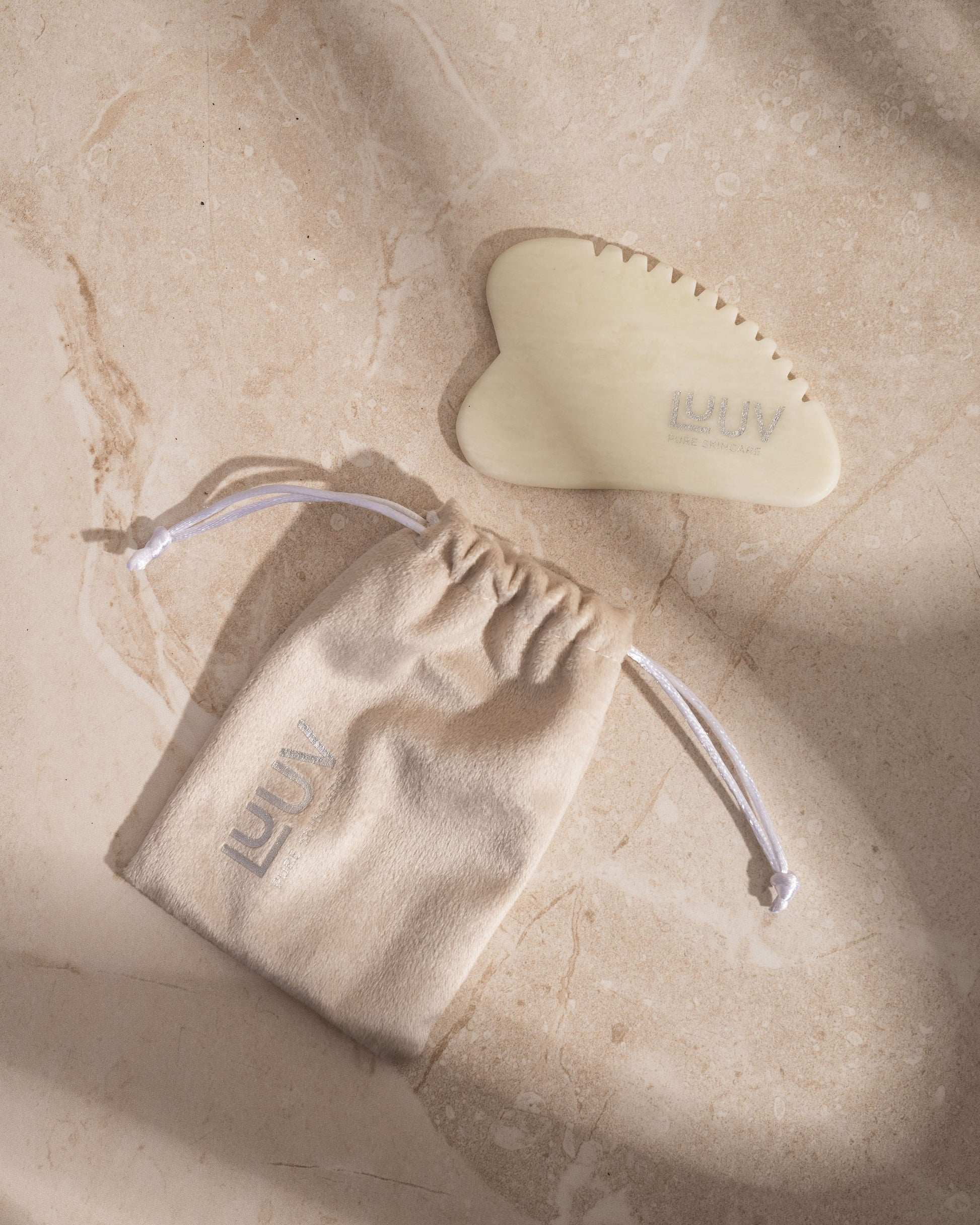 handcrafted white jade gua sha tool resting on soft fabric for a comforting body massage