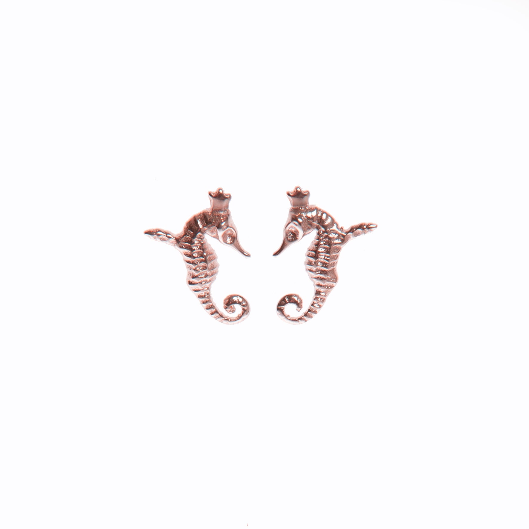 bold close-up of enchanted hippocamp rose gold earrings on a dark background