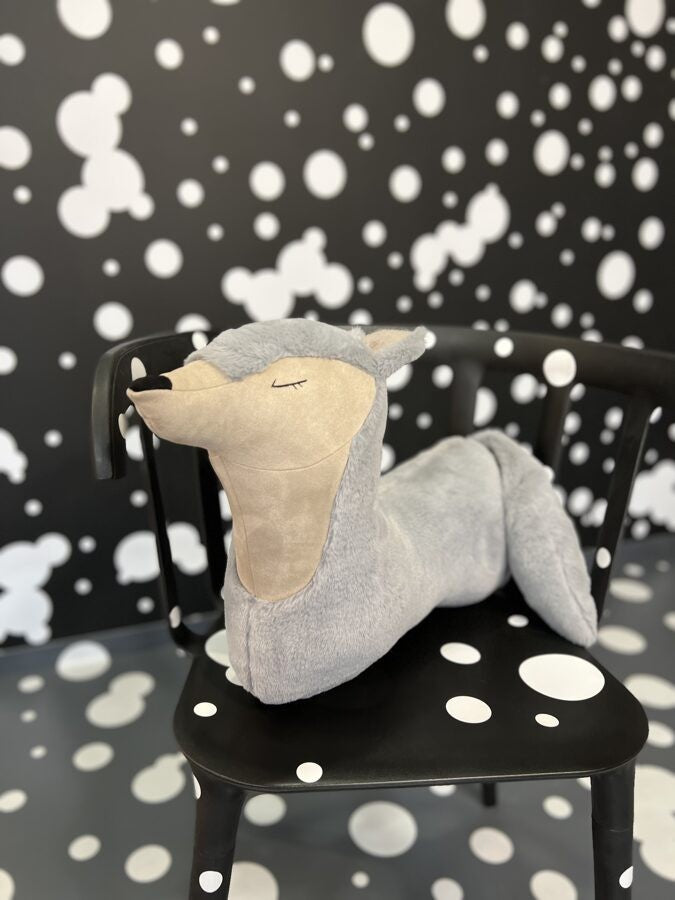 a playful grey wolf toy pillow mid-tumble on a sunny nursery floor