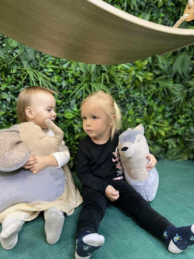 grey wolf pillow toy shown in use as a comfortable headrest for a child