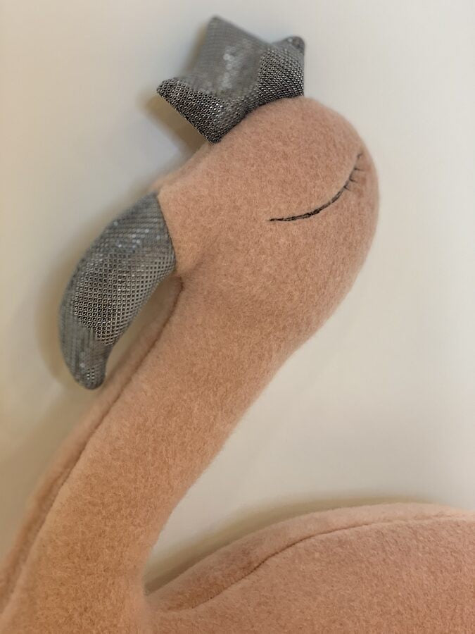a softly lit handmade pink flamingo plush with a tiny crown, nestled in cozy llama wool for a comforting bedtime companion