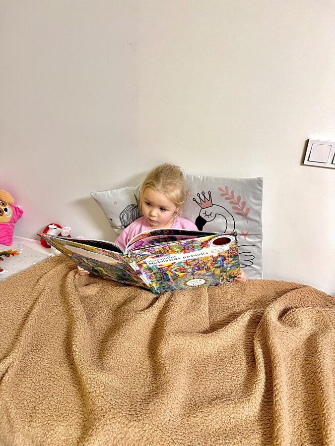 a playful toddler peeking out from a mountain of super soft sand-colored teddy blanket