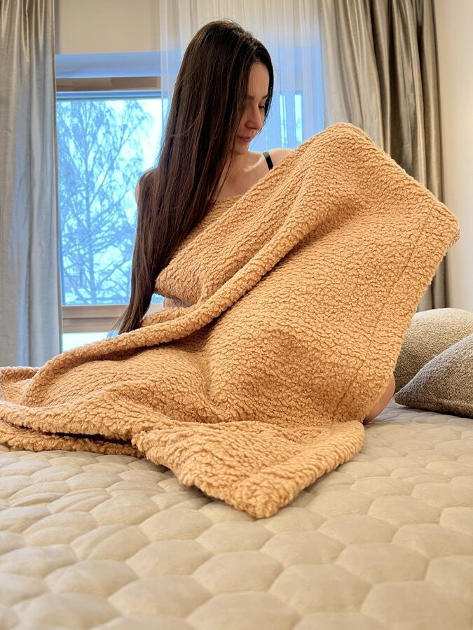 sand-colored teddy blanket laid flat on a bed to show its dimensions and soft texture