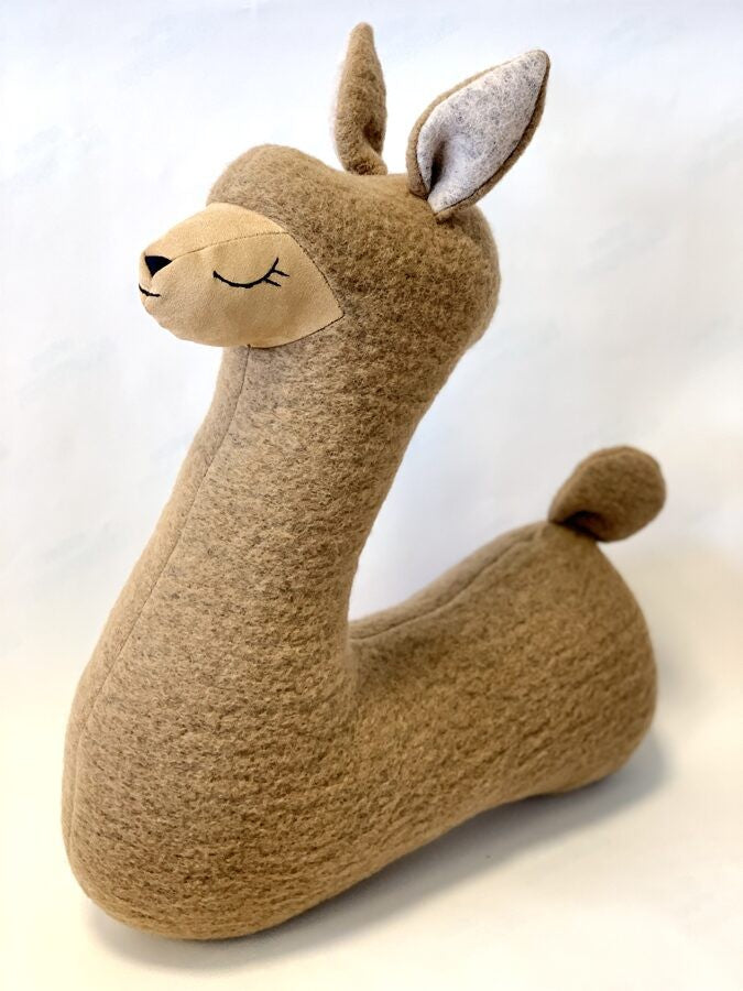 a soft brown alpaca plush pillow resting gently on a cozy nursery chair