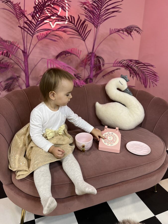 a soft handmade swan toy with a crown being gently cradled in cozy lamplight