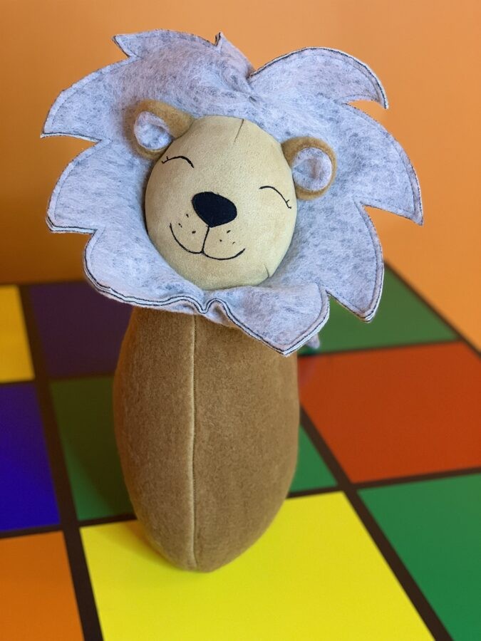 handmade lion cuddle pillow in warm nursery light on a cozy chair