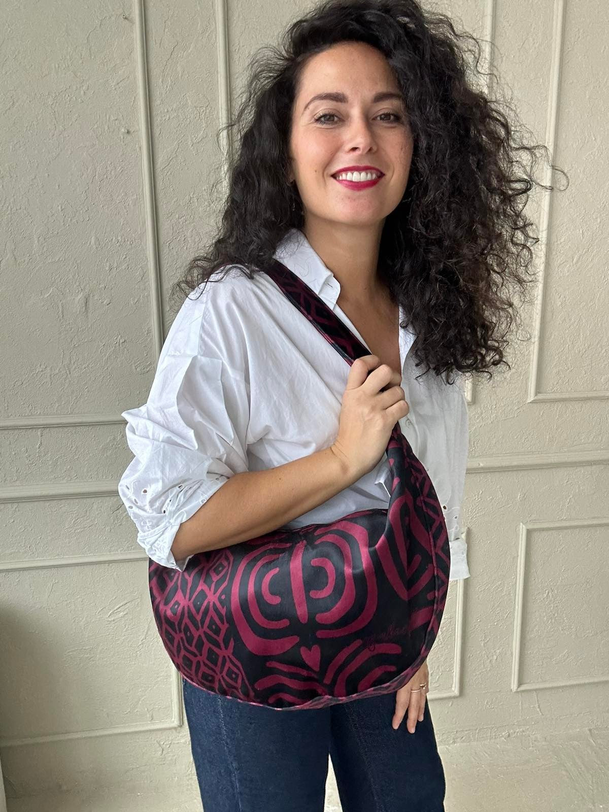 a soft burgundy velour hobo bag resting gently on a cozy surface, its slouchy form inviting a comforting touch